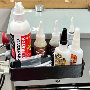 May include: A black plastic organiser with six bottles of glue. The bottles are labelled "Titebond", "Starbond", and "Mercury Adhesives".