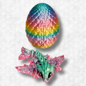 Peut inclure: Un &oelig;uf de dragon iridescent arc-en-ciel avec un dragon assorti &eacute;closant de l'&oelig;uf. Le dragon est de couleur vert clair avec des ailes roses et un corps violet clair.