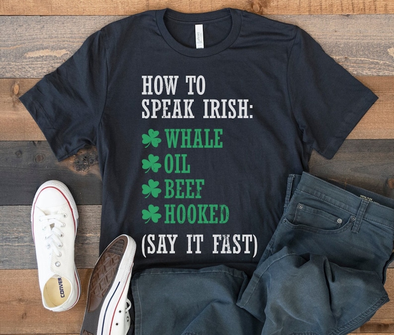 May include: A black t-shirt with white text that reads "How to Speak Irish: * Whale * Oil * Beef * Hooked (Say it Fast)". The text is surrounded by shamrock symbols.