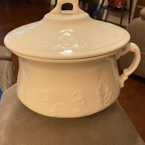 May include: White ceramic chamber pot with a lid and a handle. The pot has a floral design.