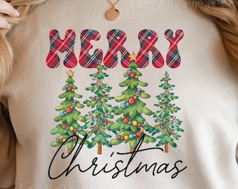 Op de afbeelding: Een beige sweatshirt met de woorden "Merry Christmas" in rood en zwart geruite letters. Het woord "Merry" staat in grote, gestileerde letters en het woord "Christmas" staat in een cursief schrift. Er zijn vijf groene kerstboom met kleurrijke ornamenten en lampjes.