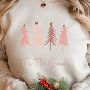 Könnte beinhalten: Ein weißer Pullover mit einem pinkfarbenen und braunen Weihnachtsbaumdesign und dem Text "Tis the Season".