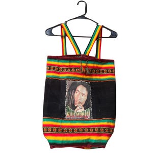 May include: A black tote bag with a portrait of Bob Marley. The bag features red, yellow, and green stripes at the top and bottom, with matching straps. The text "BOB MARLEY" is printed below the portrait.