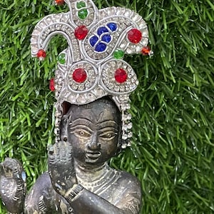 Könnte beinhalten: Eine dunkelbraune Statue einer Gottheit, die eine silberne Krone mit roten, blauen und grünen Edelsteinen trägt. Die Krone ist mit Strasssteinen verziert.
