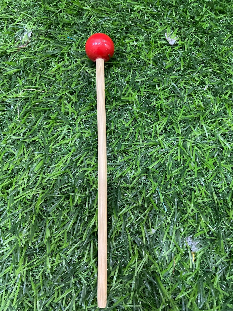 May include: A wooden mallet with a red rubber head. The mallet is used for playing musical instruments.