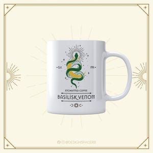 Puede incluir: Taza de café de cerámica blanca con un diseño de serpiente verde y amarilla y el texto "Enchanted Coffee Basilisk Venom". La taza tiene un asa y el diseño incluye el texto "Est. 1991".
