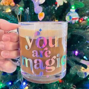 May include: A clear glass mug with a handle, filled with coffee. The mug has a holographic sticker that reads "You are magic".