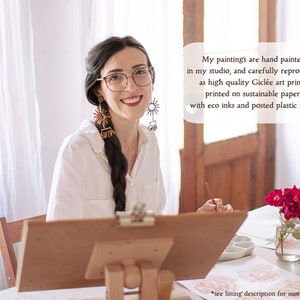 A photo of the artist in her studio, painting flowers. The text reads - My paintings are hand painted in my studio, and carefully reproduced as high quality Giclée art prints, printed on sustainable paper, with eco ink and posted plastic free.