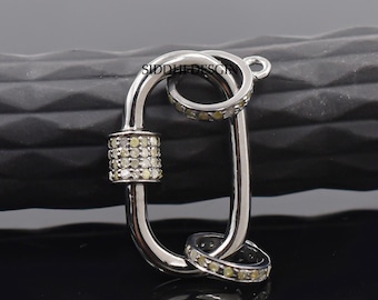 Puede incluir: Cierre de metal plateado con un diseño engastado con diamantes. El cierre es de forma ovalada y tiene un pequeño bucle en la parte superior. El cierre es un cierre de joyería popular para collares, pulseras y llaveros.
