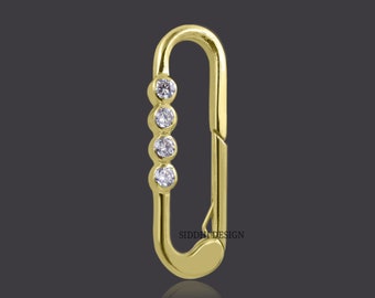 May include: Gold-toned metal clasp with a row of four clear round stones.  The clasp is shaped like a small oval with a hook on one side.  The text "SIDDHI DESIGN" is visible on the clasp.