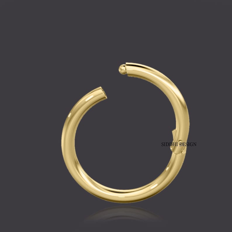 May include: Gold hoop earring with a ball closure. The earring is open and ready to be worn.
