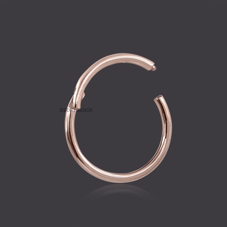 May include: A rose gold hoop earring with a seamless, continuous design. The earring is made of metal and has a smooth, polished finish.