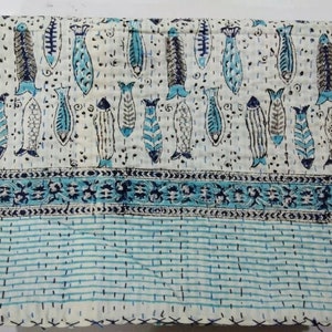 May include: White cotton quilt with a blue and black fish pattern. The quilt has a blue and white striped border.