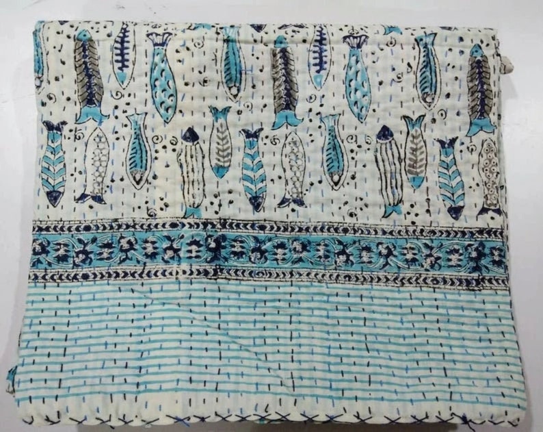 May include: White cotton quilt with a blue and black fish pattern. The quilt has a blue and white striped border.