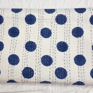 May include: White cotton quilt with a blue polka dot pattern. The quilt is hand-stitched and has a traditional kantha design.