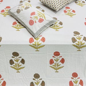 May include: White cotton bed sheet with a floral print featuring pink and brown flowers. The sheet is paired with two pillowcases with the same floral print.
