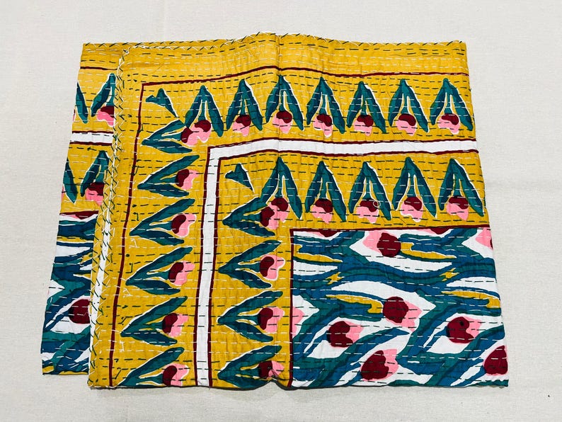 May include: A yellow, white, and blue kantha quilt with a floral pattern. The quilt is made of cotton and is hand-stitched.