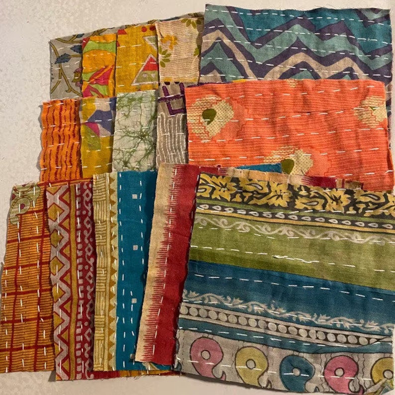 K&ouml;nnte beinhalten: Eine Sammlung bunter Stoffquadrate mit verschiedenen Mustern, darunter florale, geometrische und gestreifte Designs. Die Quadrate sind mit wei&szlig;em Garn zusammengen&auml;ht und erzeugen einen Patchwork-Effekt.