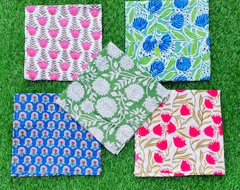 Pode incluir: Cinco guardanapos quadrados de algodão com padrões florais. Os guardanapos apresentam diferentes desenhos florais em tons de rosa, azul, verde e branco.