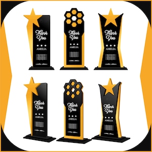 May include: Six black and gold trophies with star and honeycomb designs. Each trophy has the words "Thank You" and the name "AMELIA" in white script. The trophies are on a white background.
