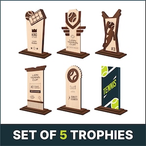 May include: Set of five wooden tennis trophies with brown bases. The trophies feature different designs, including a tennis racket, a tennis ball, and a tennis net. The trophies are labelled with the text "King of Tennis", "Lion Tennis Cup", "Club Logo", and "Tennis".