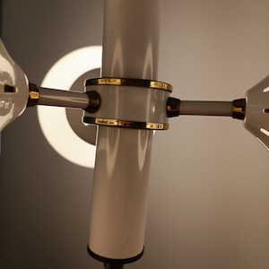 Peut inclure: Un lustre blanc et dor&eacute; avec une colonne centrale cylindrique et des bras rayonnants. Le luminaire pr&eacute;sente des accents dor&eacute;s et une source de lumi&egrave;re circulaire. Le design est moderne et &eacute;l&eacute;gant, adapt&eacute; &agrave; l'&eacute;clairage int&eacute;rieur.