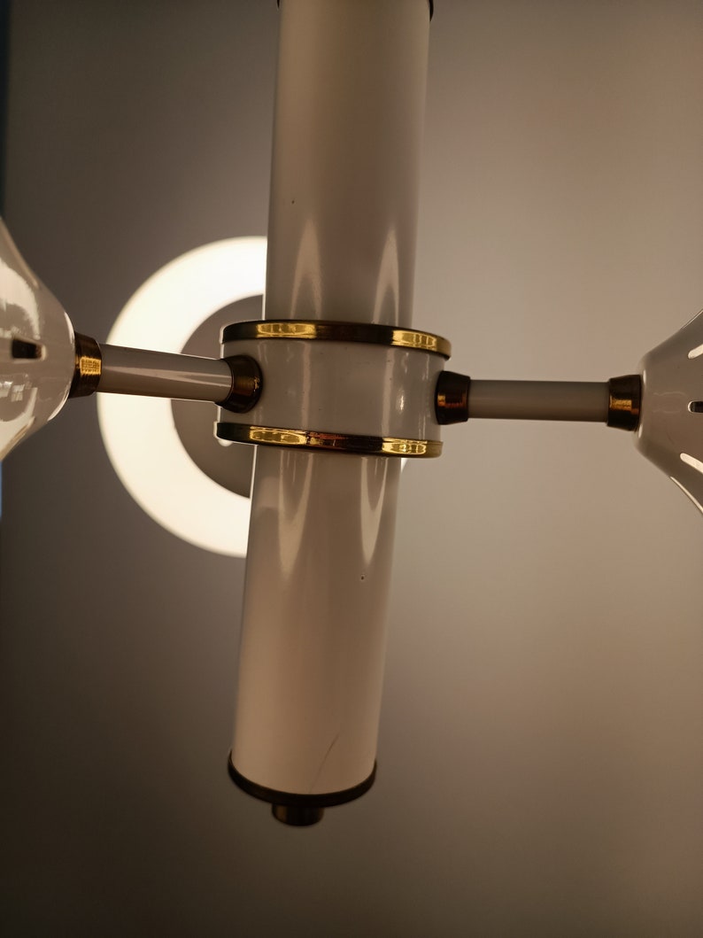 Peut inclure: Un lustre blanc et dor&eacute; avec une colonne centrale cylindrique et des bras rayonnants. Le luminaire pr&eacute;sente des accents dor&eacute;s et une source de lumi&egrave;re circulaire. Le design est moderne et &eacute;l&eacute;gant, adapt&eacute; &agrave; l'&eacute;clairage int&eacute;rieur.