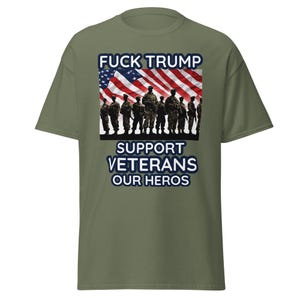 Peut inclure: T-shirt vert olive avec un motif graphique. Le texte "FUCK TRUMP" est au-dessus d'un drapeau américain et d'un groupe de soldats. Le texte "SUPPORT VETERANS OUR HEROES" est en dessous.