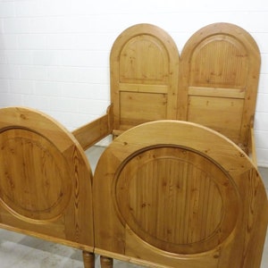 Könnte beinhalten: Ein Holzbettgestell mit gewölbten Kopfteilen und abgerundeten Fußenden. Der Rahmen ist aus Naturholz mit einer hellbraunen Oberfläche.