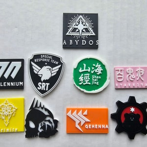 Può includere: Nove patch diversi con vari disegni e testi. I patch sono neri, bianchi, verdi, rosa e grigi. Il testo sui patch include "77 MILLENNIUM", "SPECIAL RESPONSE TEAM SRT", "ABYDOS", "山海經 Shan hai jing", "HYAKKITAKO", "Trinite", e "GEHENNA".