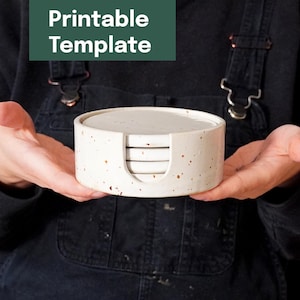 Op de afbeelding: Een set van vier bespikkelde keramische onderzetters met een bijpassende houder. De onderzetters en houder zijn gebroken wit met bruine spikkels. De tekst "Printable Template" staat in een groene doos.