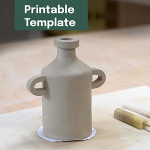 Puede incluir: Un jarrón de cerámica de color beige claro con dos asas curvas y un cuello estrecho. El jarrón se asienta sobre una base de papel blanco. Las palabras "Printable Template" están en un rectángulo verde en la esquina superior izquierda.