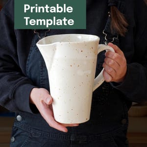 Puede incluir: Jarra de cerámica color crema con un pico ancho y asa. La jarra tiene un diseño moteado con manchas marrones. El texto "Printable Template" está en un rectángulo verde encima de la jarra.