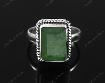 Puede incluir: Un anillo de plata con una piedra preciosa verde engastada en un bisel cuadrado. El anillo tiene un diseño de cuerda alrededor del bisel.