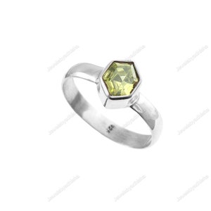 Peut inclure: Une bague en argent avec une pierre précieuse verte hexagonale. La bague est marquée du numéro "925" à l'intérieur de la bande.