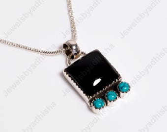 Può includere: Una collana con catena d'argento con un ciondolo in onice nero decorato con tre pietre turchesi.