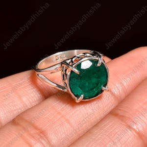 May include: A silver ring with a green gemstone set in a delicate filigree design. The ring is marked "925" on the band.