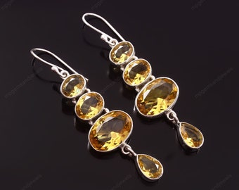 Pode incluir: Um par de brincos de prata pendurados com pedras preciosas de citrino amarelo. Os brincos têm cinco pedras preciosas de forma oval de tamanhos diferentes, com uma pedra preciosa em forma de lágrima na parte inferior.