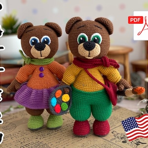 Puede incluir: Dos osos de peluche de ganchillo hechos a mano. Uno lleva una blusa naranja, una falda morada y una bufanda verde, sosteniendo una paleta. El otro lleva una camisa amarilla, pantalones verdes y una bufanda roja, sosteniendo un pincel. La palabra "PATTERN" está escrita verticalmente a la izquierda.
