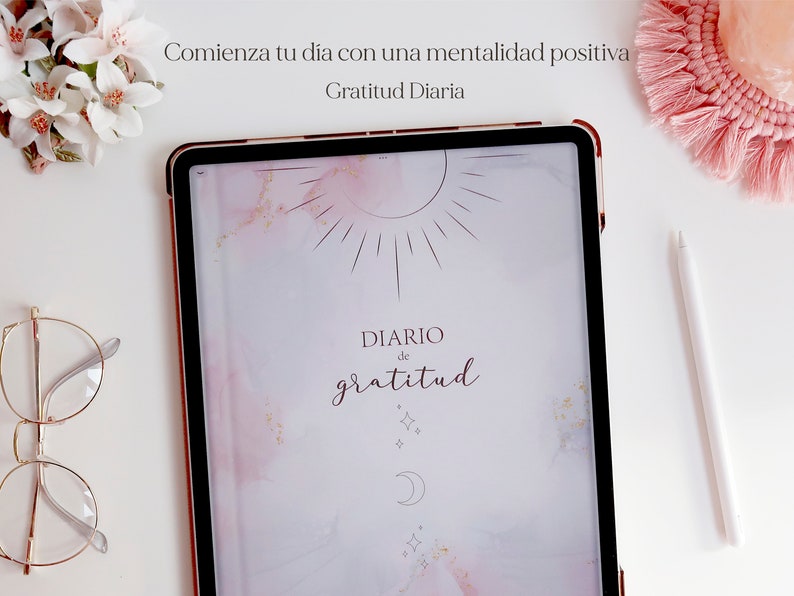 Pu&ograve; includere: Un tablet digitale rosa e bianco con una cornice color oro rosa. Lo schermo mostra uno sfondo acquerellato rosa e bianco con un design di sole e luna. Il testo "DIARIO de gratitud" &egrave; scritto in corsivo sullo schermo. Il testo "Comienza tu dia con una mentalidad positiva" &egrave; scritto sopra il tablet. Il testo "Gratitud Diaria" &egrave; scritto sotto il tablet.