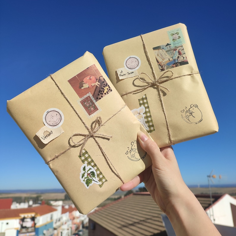May include: Two brown paper packages wrapped with twine and decorated with stickers, stamps, and labels. The packages are tied with twine and have a rustic, handmade aesthetic.