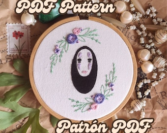 May include: A hand-stitched embroidery hoop featuring a black figure with a pale face, surrounded by purple and pink flowers and green leaves. The text "PDF Pattern" and "Patrón PDF" are displayed in a vintage font.