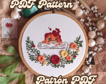 May include: Embroidered hoop art featuring a cartoon fire character on a log, surrounded by floral embroidery. The design includes red, orange, and yellow flowers with green leaves. The text "PDF Pattern" is arched above the design.