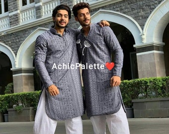 Op de afbeelding: Twee mensen dragen bijpassende, grijs gepatroneerde, langarmige shirts met witte broeken. De shirts hebben een subtiel paisley-patroon. De mannen staan ​​naast elkaar en glimlachen.