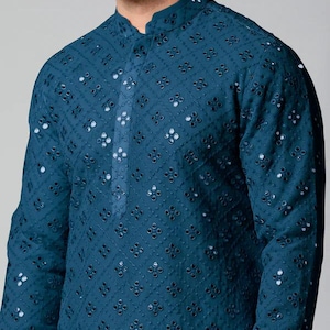 Puede incluir: Una kurta azul turquesa con un dise&ntilde;o tradicional bordado con peque&ntilde;os espejos redondos.