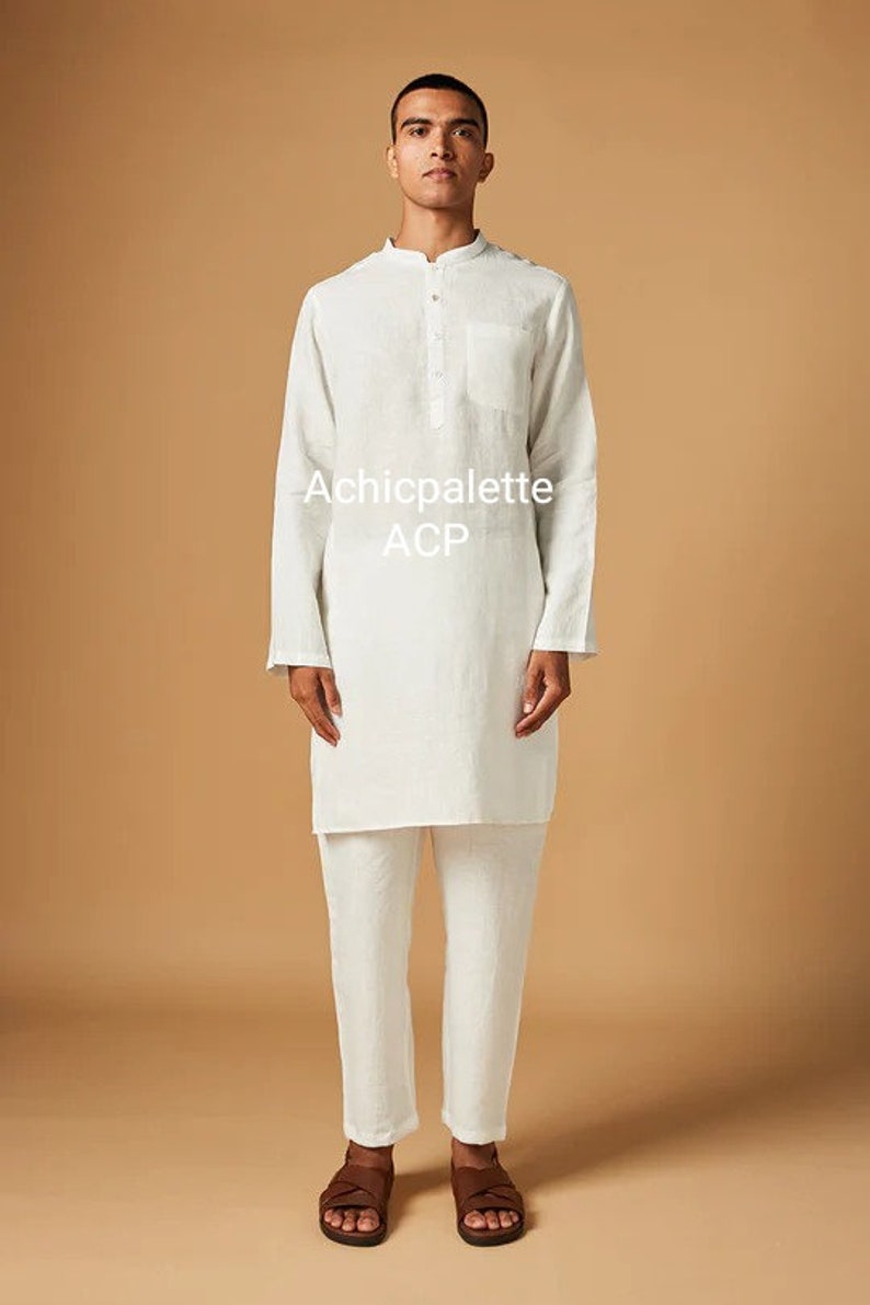Puede incluir: Una kurta de lino blanco con cuello mandar&iacute;n y cierre de bot&oacute;n &uacute;nico. La kurta tiene un bolsillo en el pecho y mangas largas. El modelo lleva pantalones de lino blanco y sandalias marrones. El texto "Achicpalette ACP" est&aacute; impreso en la kurta.