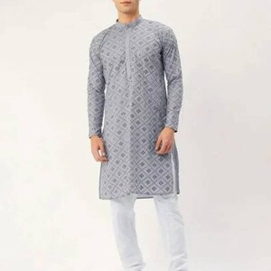 Puede incluir: Una kurta gris de manga larga con un patr&oacute;n geom&eacute;trico y adornos plateados. La kurta tiene un cuello mandar&iacute;n y un cierre de bot&oacute;n. El modelo lleva pantalones blancos y sandalias marrones.