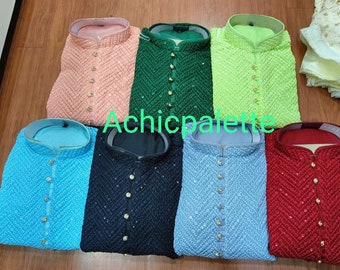 Pode incluir: Oito kurtas de diferentes cores com bordados intrincados e botões dourados. As kurtas estão dispostas em uma fila sobre uma superfície de madeira.