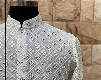 Puede incluir: Camisa blanca de manga larga con cuello alto y un patrón de diamantes de pequeños espejos redondos.