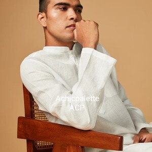 Puede incluir: Un hombre con una camisa blanca de lino est&aacute; sentado en una silla de madera con un asiento de mimbre tejido. La camisa tiene un cuello mandar&iacute;n y un cierre de bot&oacute;n &uacute;nico. El texto "Achicpalette ACP" es visible en la camisa.